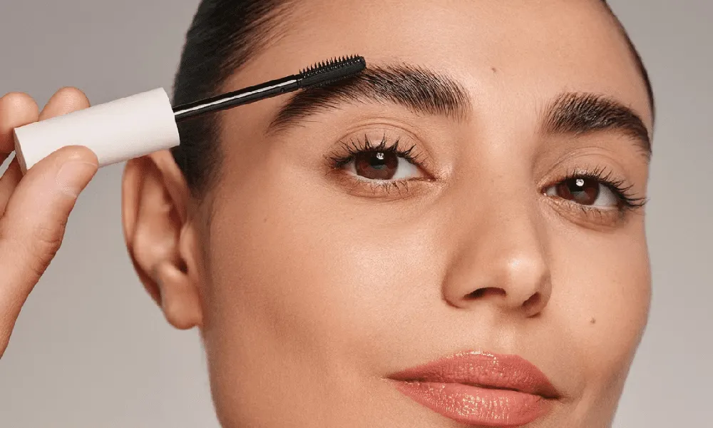 زن جوان که ابروی راست خود را رنگ می کند